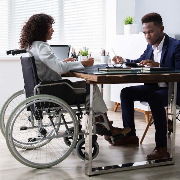 woman in wheelchair working in office with man