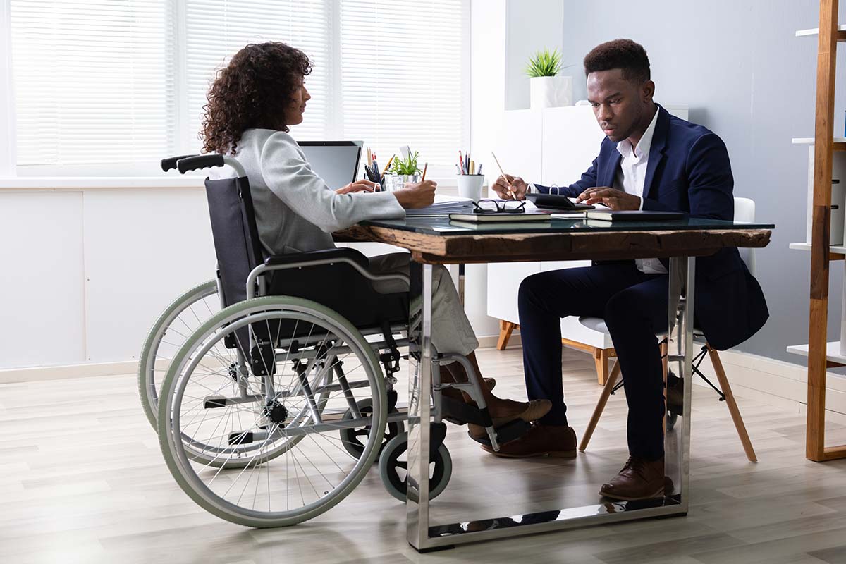 woman in wheelchair working in office with man