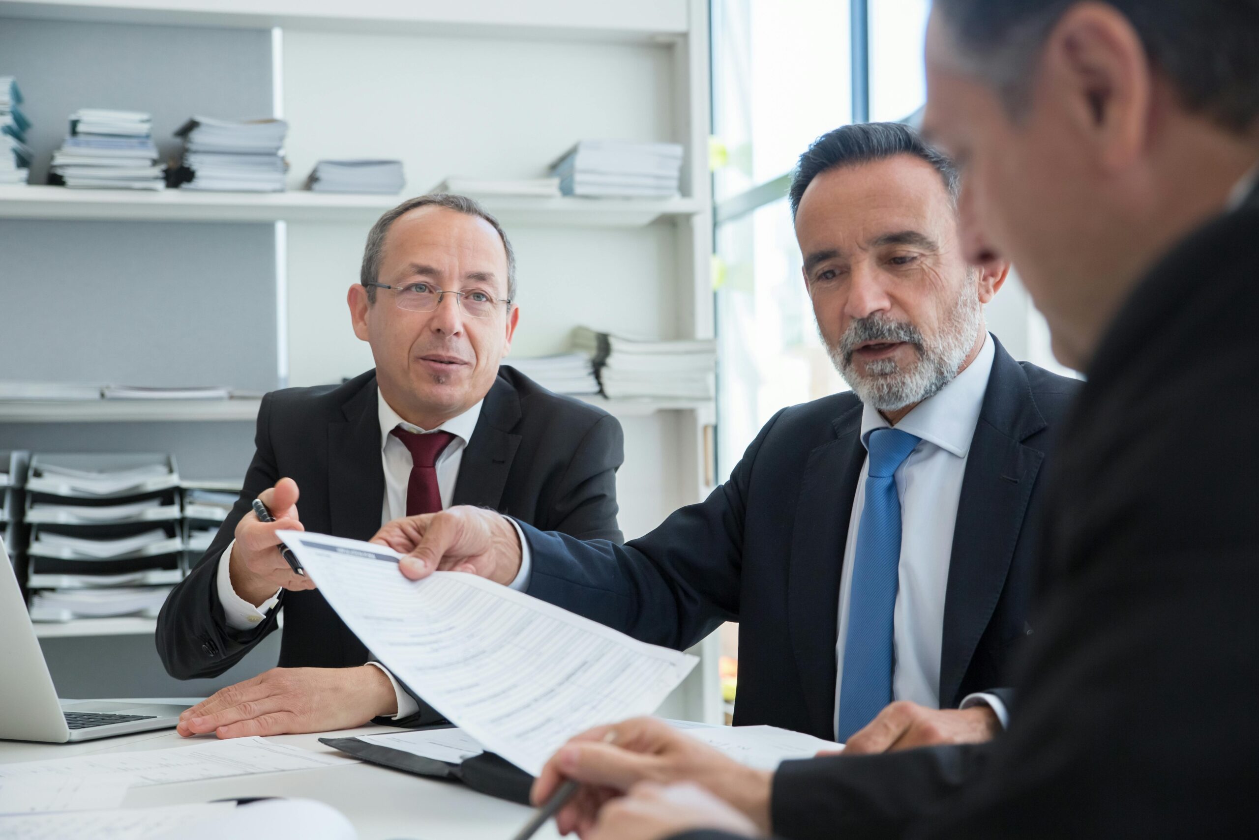 An attorney (center) reviews a severance contract with a client (right)