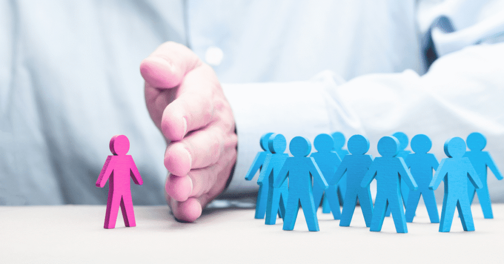 Workplace sexual orientation discrimination illustrated by a hand separating a pink figure from blue figures, highlighting isolation in the workplace.