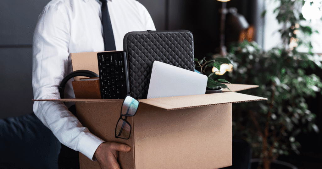 Professional carrying office belongings in box after probationary termination - documenting proper exit procedures under termination laws.