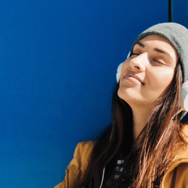 A young woman relaxes outdoors with headphones during her medical leave for mental health.