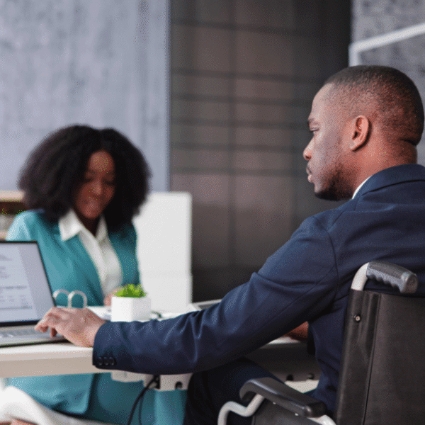 Professional workplace disability access with an employee in a wheelchair working on a laptop.