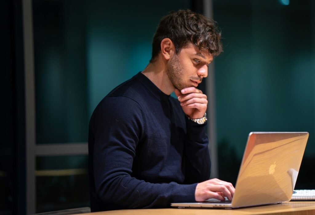 A man working late at a laptop, reflecting on workplace issues that may relate to retaliation claims beyond protected classes.