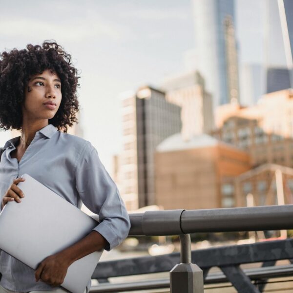 Professional employee holding a laptop in an urban setting, representing leadership decision-making and flexible work policies in modern workplaces.