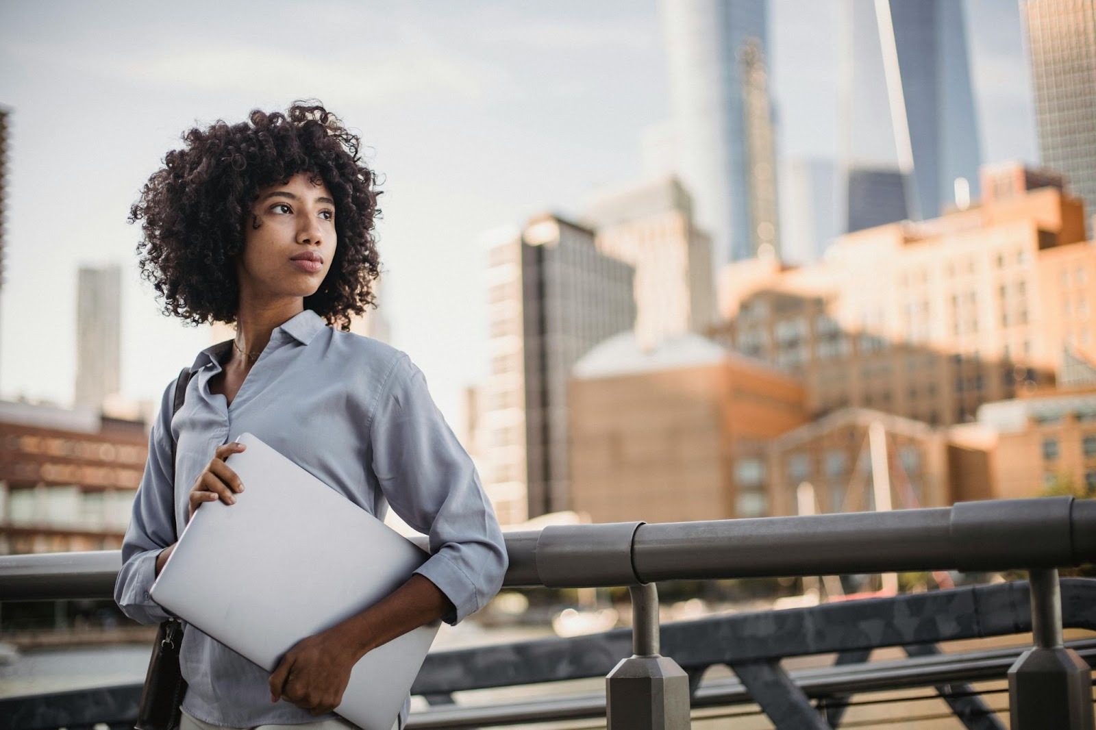 Professional employee holding a laptop in an urban setting, representing leadership decision-making and flexible work policies in modern workplaces.